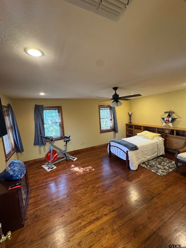 bedroom featuring ceiling fan, a textured ceiling, and dark hardwood / wood-style flooring