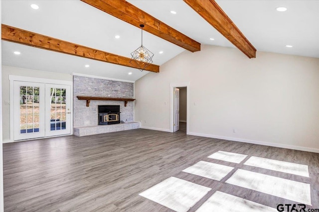 unfurnished living room with hardwood / wood-style floors, lofted ceiling with beams, and a brick fireplace