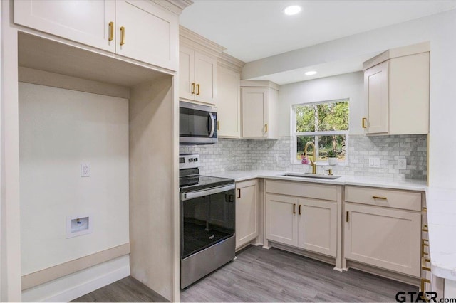 kitchen with backsplash, sink, light wood-type flooring, and appliances with stainless steel finishes