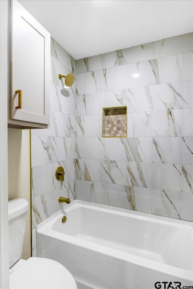 bathroom with toilet and tiled shower / bath