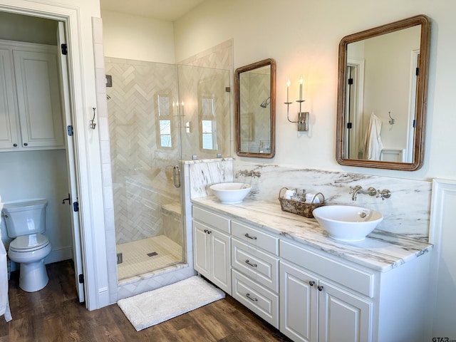 full bath with double vanity, a shower stall, a sink, and wood finished floors