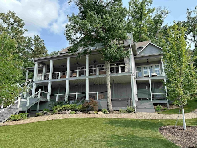 back of property featuring a chimney, a lawn, stairway, ceiling fan, and a balcony