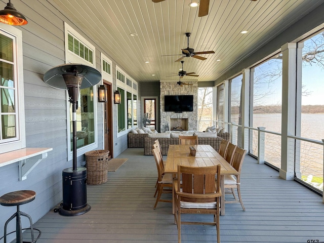 sunroom / solarium featuring wooden ceiling, an outdoor stone fireplace, and a ceiling fan