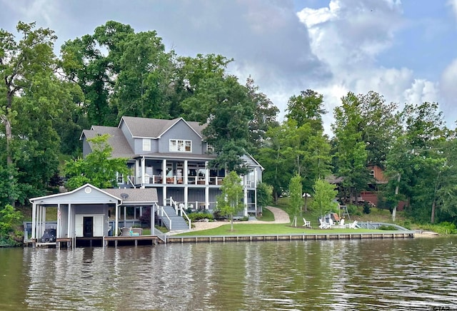 back of house featuring a water view, a lawn, and stairs