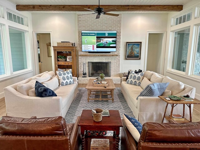 living area with a brick fireplace, ceiling fan, wood finished floors, wooden ceiling, and beamed ceiling