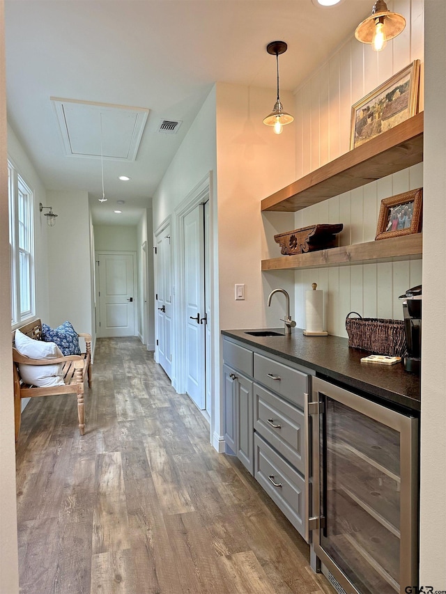 interior space featuring visible vents, attic access, a sink, wood finished floors, and beverage cooler