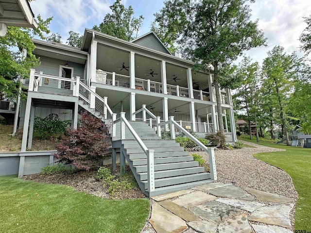 view of front facade with a front yard, ceiling fan, and stairway