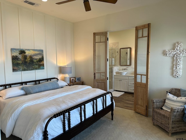 bedroom with visible vents, ceiling fan, light carpet, and ensuite bathroom