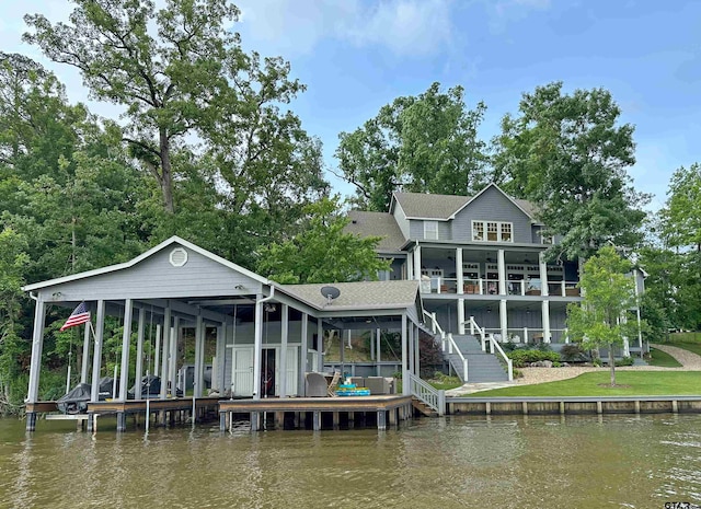 back of property with roof with shingles, stairway, and a water view