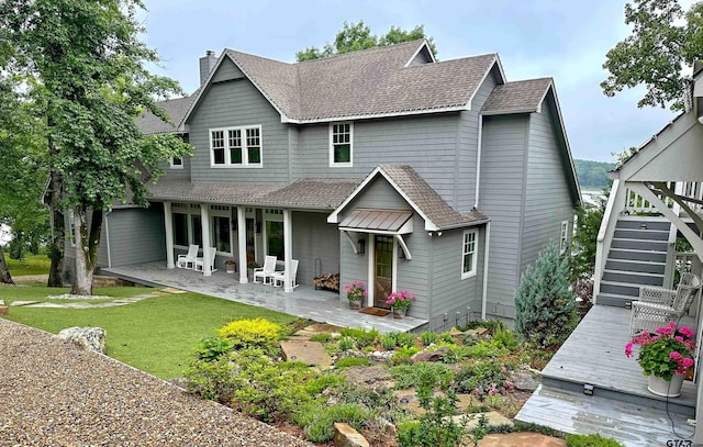 back of house with a patio area, a lawn, a chimney, and roof with shingles