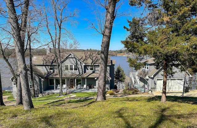 view of front of property with a water view, driveway, a garage, and a front lawn