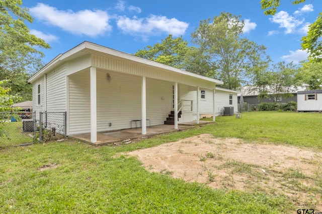 back of property with a lawn, fence, entry steps, and central AC