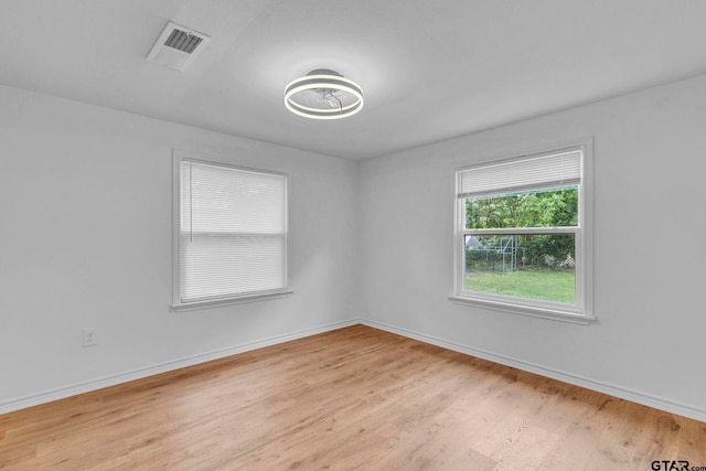 spare room with baseboards, visible vents, and light wood-type flooring