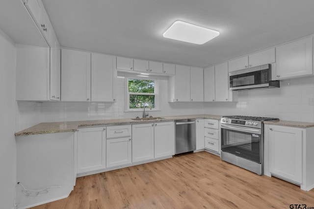 kitchen with white cabinetry, appliances with stainless steel finishes, a sink, and tasteful backsplash