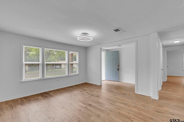 spare room with light wood-style floors, baseboards, and visible vents