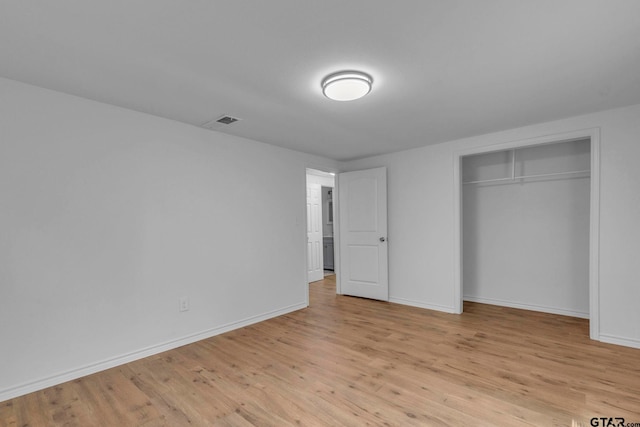unfurnished bedroom featuring visible vents, light wood finished floors, baseboards, and a closet