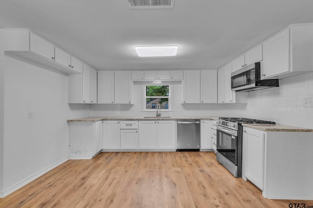 kitchen featuring visible vents, a sink, white cabinets, light wood finished floors, and stainless steel appliances