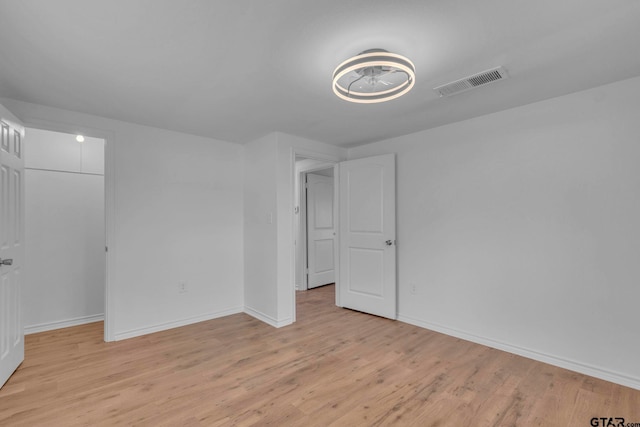 unfurnished bedroom with visible vents, a closet, baseboards, a spacious closet, and light wood finished floors