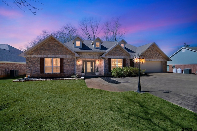 view of front of home with a garage, aphalt driveway, a front lawn, and central AC unit