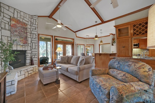 living room featuring high vaulted ceiling, beamed ceiling, a stone fireplace, and ceiling fan