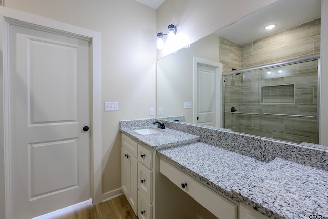 bathroom featuring wood-type flooring, vanity, and a shower with shower door