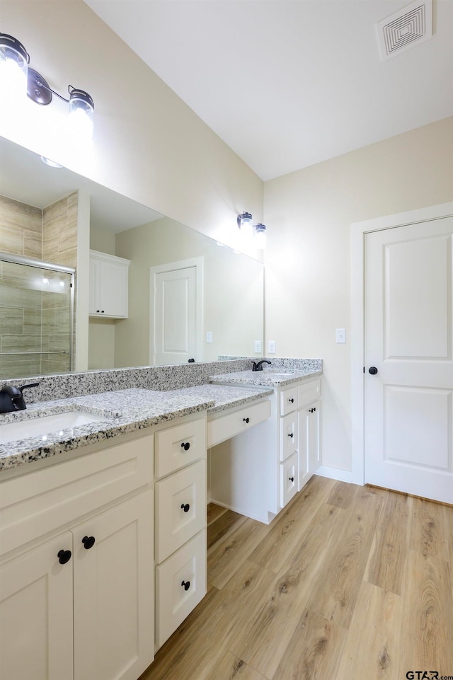 bathroom with wood-type flooring, vanity, and a shower with shower door