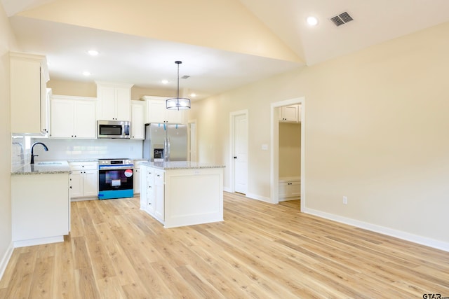 kitchen featuring stainless steel appliances, light hardwood / wood-style floors, hanging light fixtures, a center island, and white cabinets