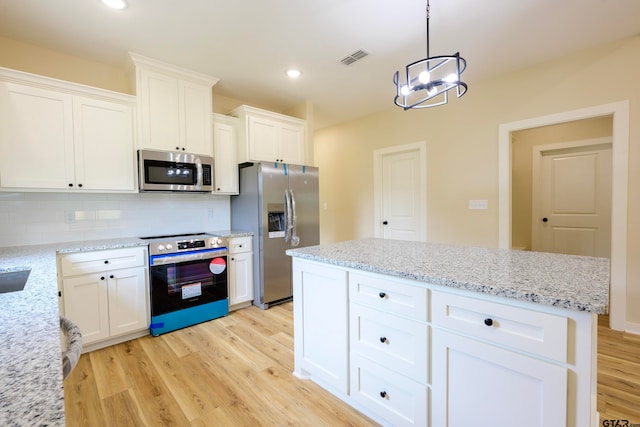 kitchen featuring white cabinetry, light wood-type flooring, stainless steel appliances, and hanging light fixtures