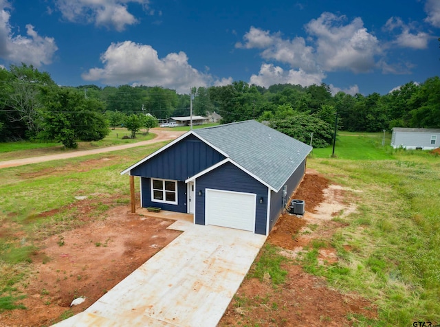 view of front of home featuring central AC, a front yard, and a garage