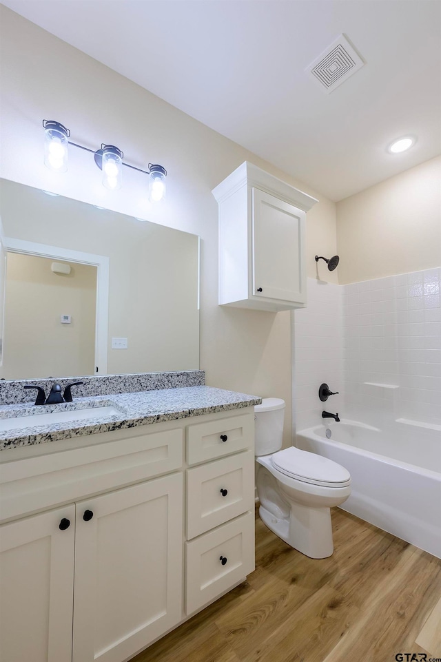 full bathroom featuring toilet, vanity, wood-type flooring, and bathing tub / shower combination