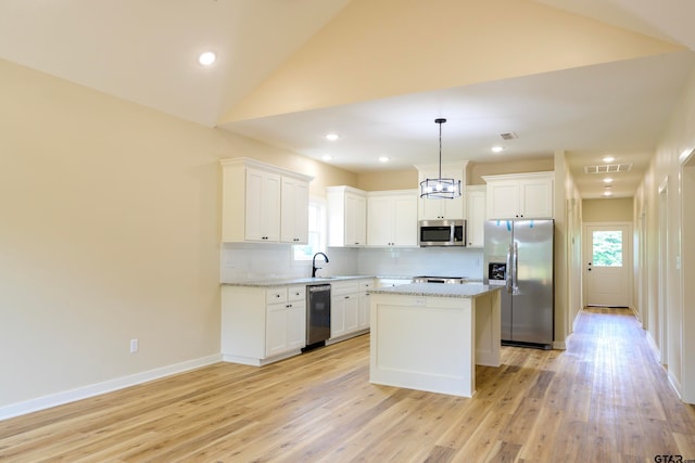 kitchen featuring white cabinets, light hardwood / wood-style flooring, a kitchen island, pendant lighting, and appliances with stainless steel finishes