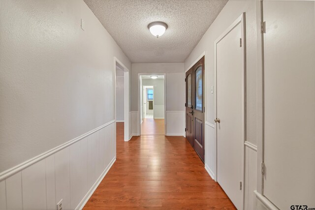 201 Karla Dr, Whitehouse, TX 75791 - hallway featuring a textured ceiling, wood finished floors, and a wainscoted wall