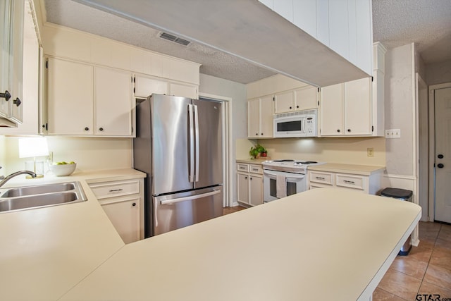 201 Karla Dr, Whitehouse, TX 75791 - kitchen featuring white appliances, a textured ceiling, light countertops, light tile patterned floors, and a peninsula