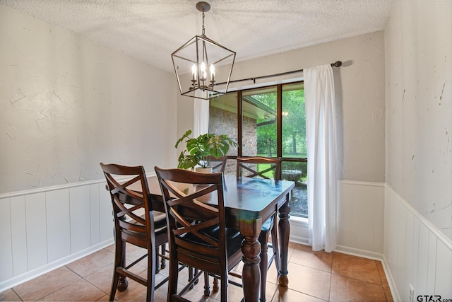 201 Karla Dr, Whitehouse, TX 75791 - dining area with a chandelier, a textured ceiling, a wainscoted wall, light tile patterned flooring, and a decorative wall