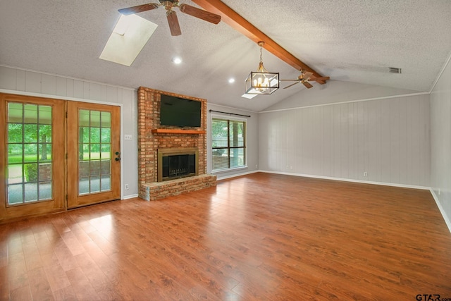 201 Karla Dr, Whitehouse, TX 75791 - unfurnished living room with ceiling fan, wood finished floors, a textured ceiling, a brick fireplace, and wooden walls