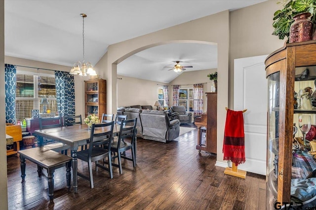 dining area featuring ceiling fan with notable chandelier, arched walkways, wood finished floors, and vaulted ceiling