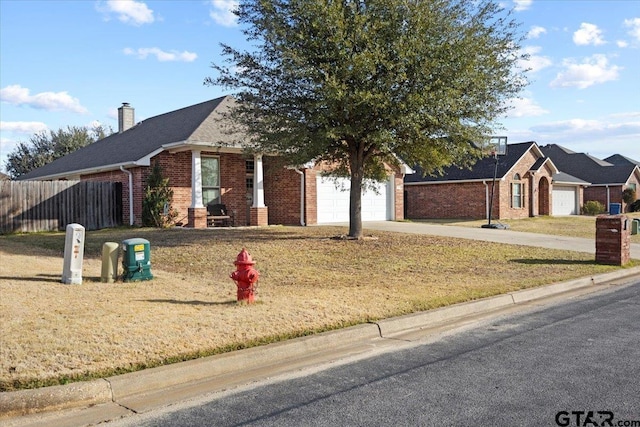 view of front of property with brick siding, an attached garage, a front lawn, fence, and driveway