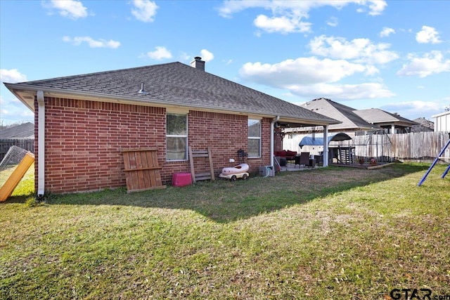 back of property with a lawn, a fenced backyard, a shingled roof, brick siding, and a chimney