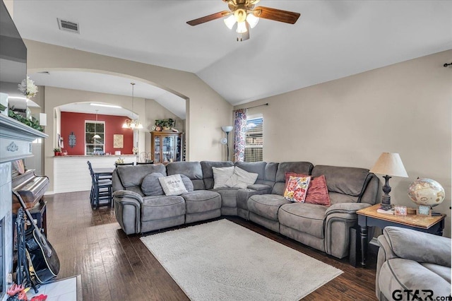 living area featuring visible vents, lofted ceiling, ceiling fan with notable chandelier, arched walkways, and dark wood-style floors