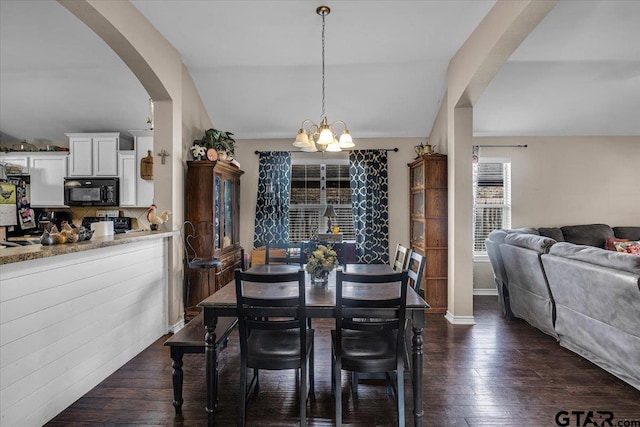 dining space with baseboards, dark wood-style floors, arched walkways, and a chandelier