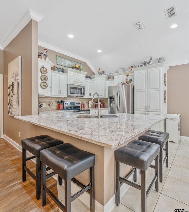 21105 Altuda Ln, Flint, TX 75762 - kitchen with stainless steel appliances, crown molding, a kitchen bar, backsplash, and white cabinetry