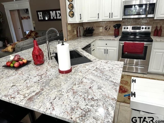 21105 Altuda Ln, Flint, TX 75762 - kitchen with appliances with stainless steel finishes, tasteful backsplash, white cabinets, and light stone countertops