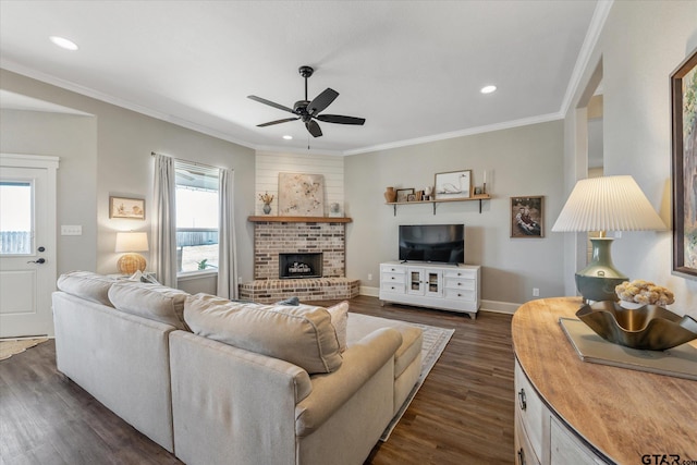 living room featuring dark wood-style floors, a brick fireplace, baseboards, and crown molding