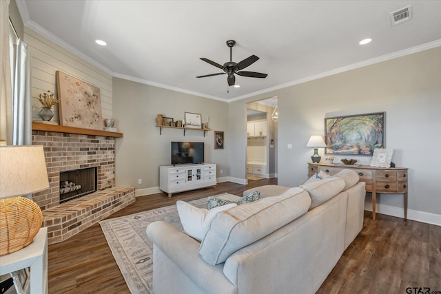 living room with a fireplace, dark wood finished floors, visible vents, ornamental molding, and baseboards