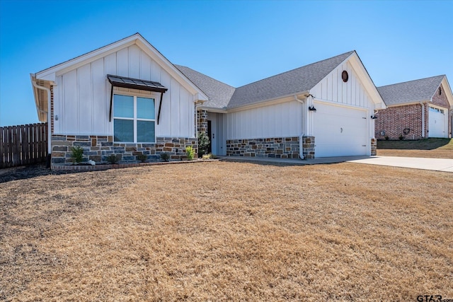 modern farmhouse style home with driveway, a shingled roof, stone siding, fence, and board and batten siding