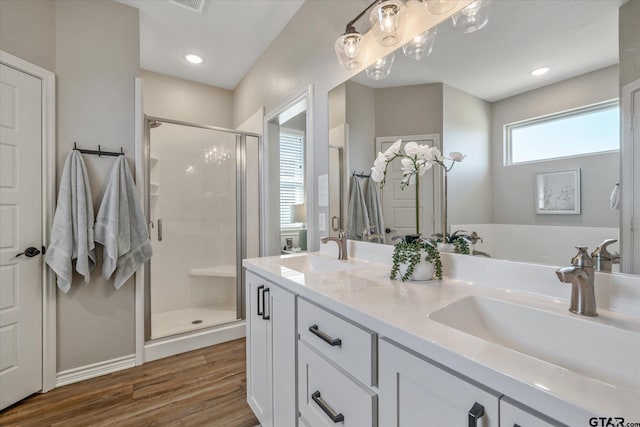 full bathroom featuring double vanity, wood finished floors, a stall shower, and a sink