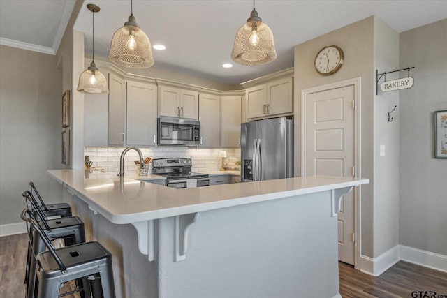 kitchen featuring appliances with stainless steel finishes, light countertops, a peninsula, and decorative backsplash