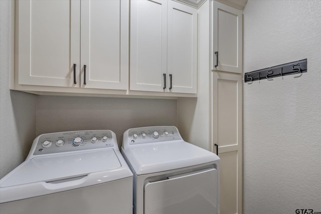 washroom with washing machine and dryer, cabinet space, and a textured wall