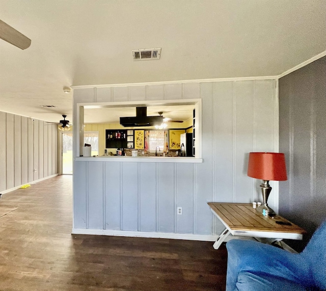 interior space with ceiling fan, black fridge, wood-type flooring, sink, and crown molding