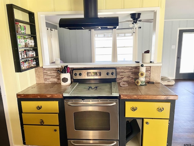 kitchen featuring decorative backsplash, ventilation hood, stainless steel electric range oven, tile countertops, and ceiling fan